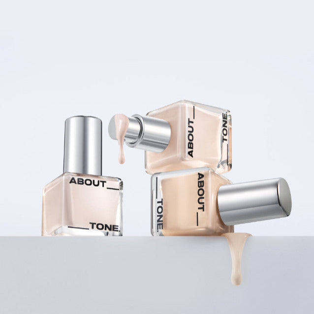ABOUT TONE Skin Layer Fit Foundation bottles with liquid foundation dripping, showcasing smooth application and finish.