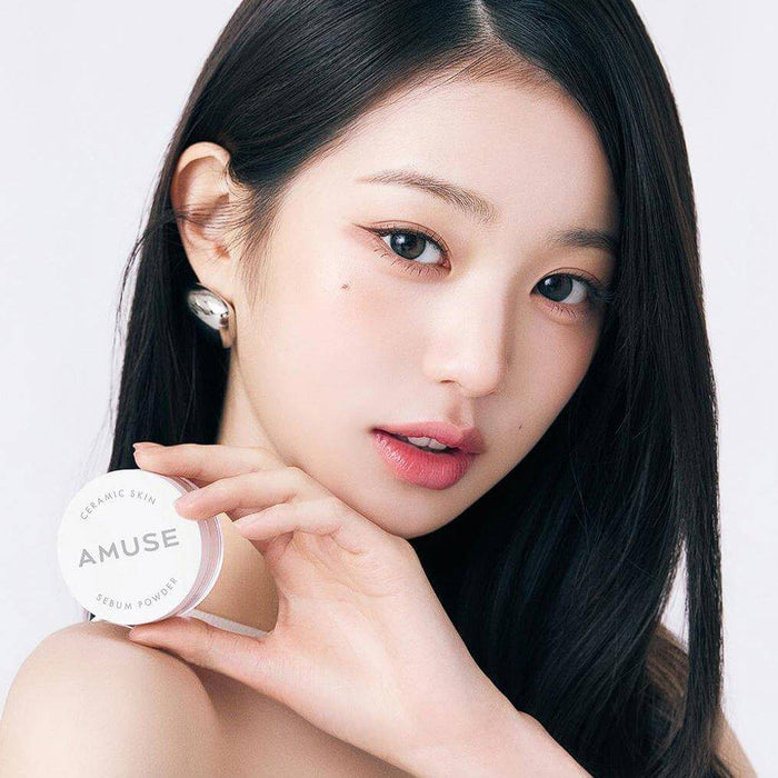 Model holding AMUSE Ceramic Sebum Powder, highlighting smooth and matte skin effect.