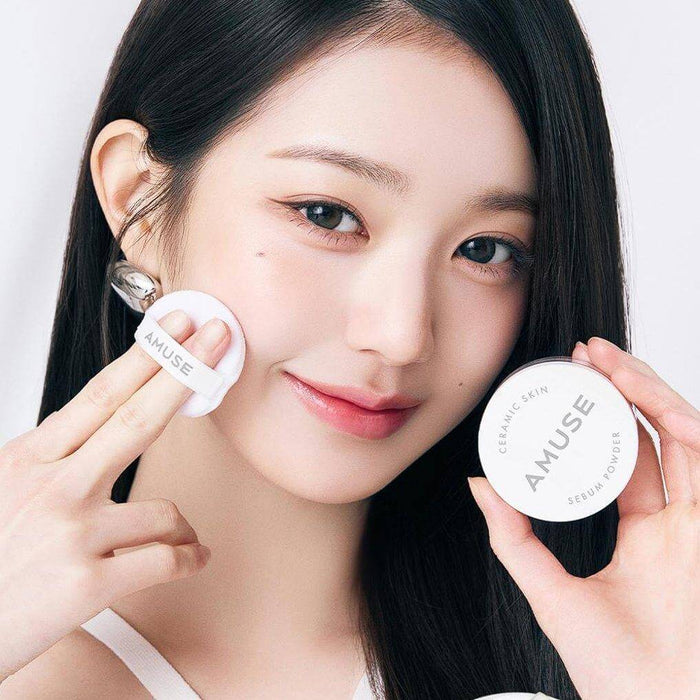 Woman applying AMUSE Ceramic Sebum Powder with puff applicator.