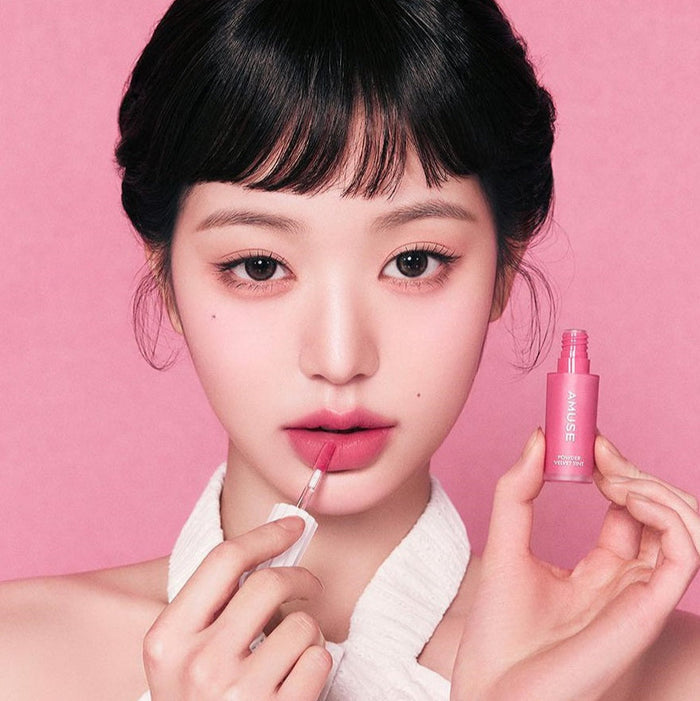 Model applying AMUSE Powder Velvet Tint, showcasing product texture and color.