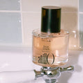 ANILLO Black Tea Nourishing Hair Essence 50ml bottle on sink by tiles