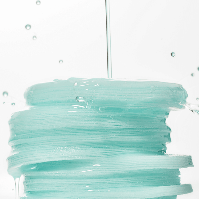 Stack of wet ANUA PDRN 100 Hyaluronic Acid Glow Pad with liquid dripping