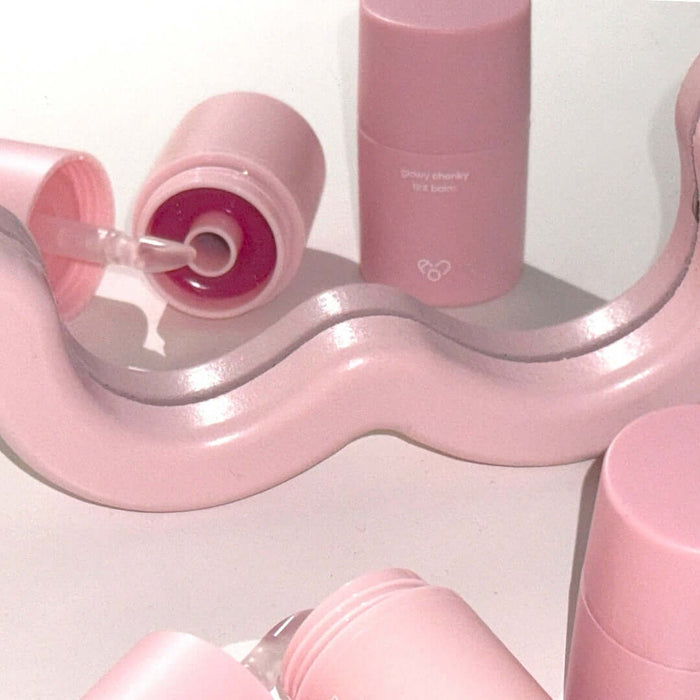 Pink AOU Glowy Chonky Tint Balm tubes with swirled design, showcasing the product's sleek and trendy packaging.