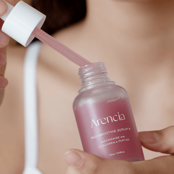Person applying ARENCIA Red Smoothie Serum 8 30ml from a dropper bottle.