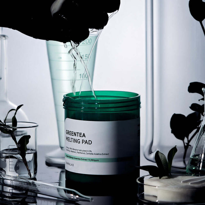 BARULAB Green Tea Melting Pad surrounded by lab equipment and green plants, illustrating skincare innovation and botanical infusion.