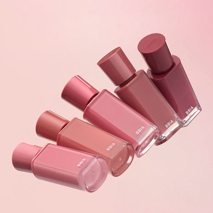 Assorted shades of BBIA Glow Tint bottles on a pink background
