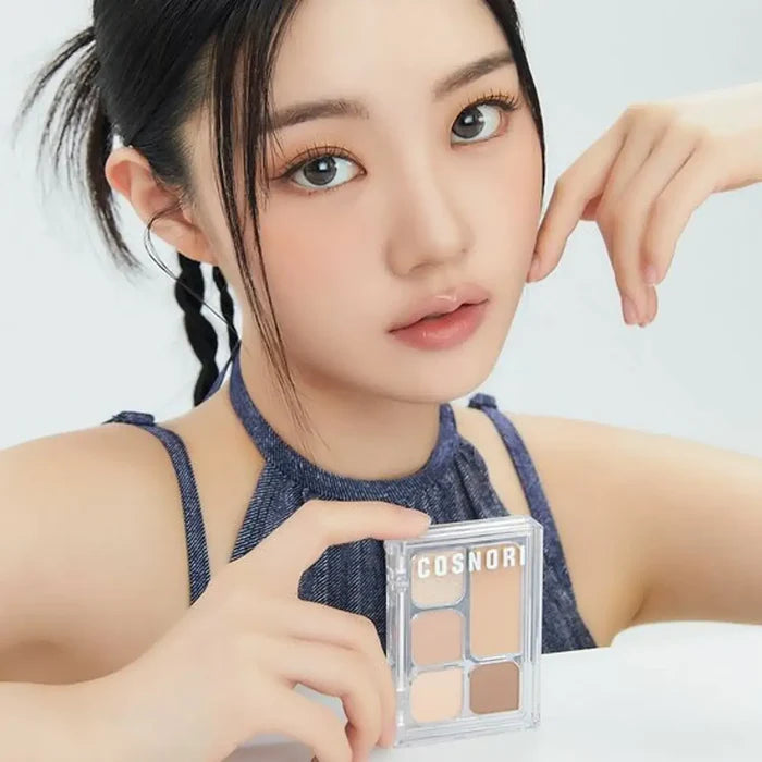 Woman holding COSNORI My Moment Eye Palette in hand, showcasing its shades for makeup application.