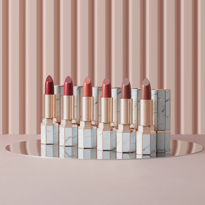 Collection of DEAR DAHLIA Lip Paradise Sheer Dew Lipstick in various shades, displayed elegantly on a reflective surface.