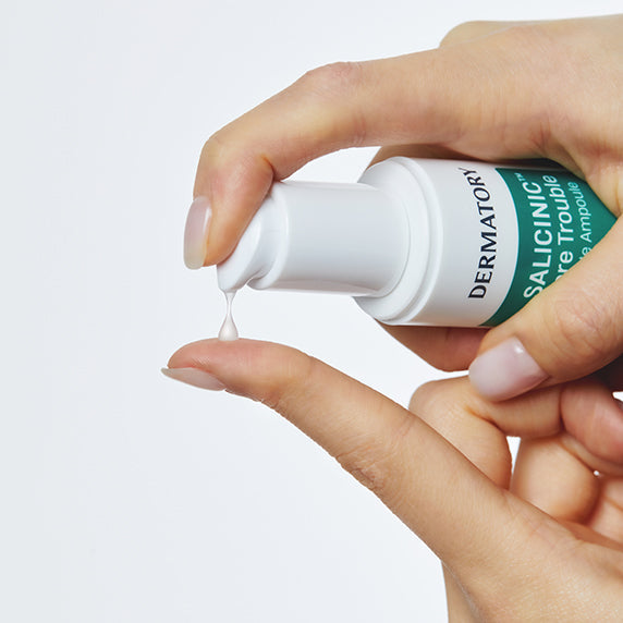 Hands dispensing DERMATORY Salicinic Pore Trouble Spicule Ampoule 50ml, focusing on skincare application.