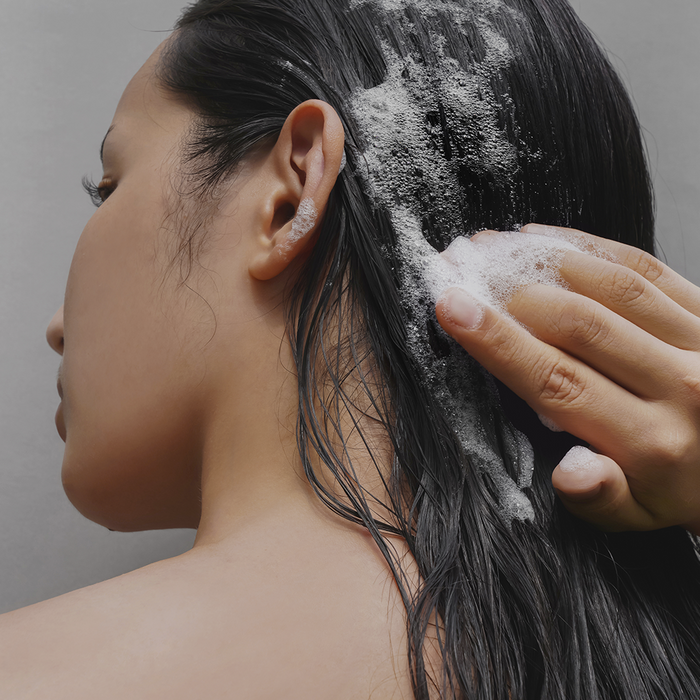 Person using DONGGUBAT Correct Shampoo Bar For Dry Skin on wet hair, creating a lather, highlighting its benefits for dry scalp care.