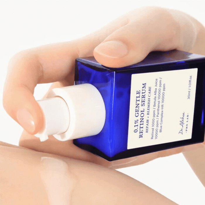Hands holding and applying DR.ALTHEA 0.1% Gentle Retinol Serum 30ml from a blue bottle.
