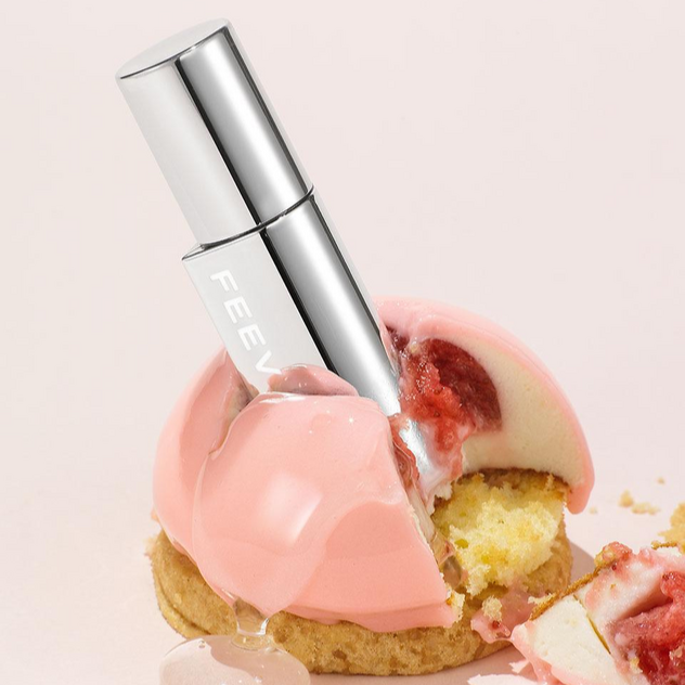 FEEV Hyper-Fit Glam Drop beauty product with a sleek design placed on a pink dessert backdrop