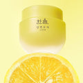 HANYUL Yuja Sleeping Mask 70ml jar with yuja fruit backdrop, bright yellow packaging.
