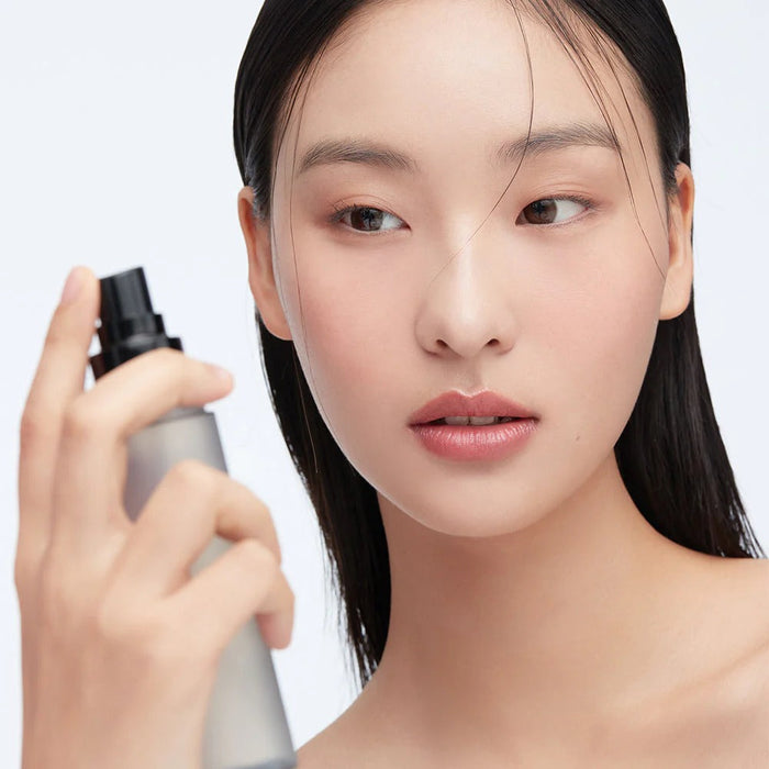 Woman using HERA Make Up Fixer 80ml for a flawless finish.