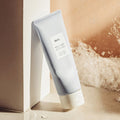 HUXLEY Cleansing Foam Deep Clean Deep Moist 150g in a bathroom setting with bubbles in the background.