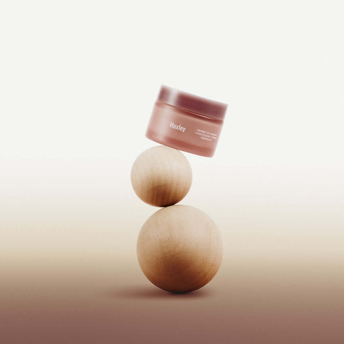 HUXLEY Conditioning Cream Preshape jar artfully balanced on wooden spheres for skincare promotion.
