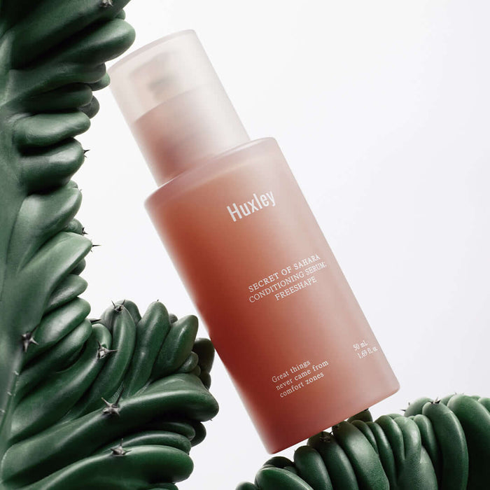 HUXLEY Conditioning Serum Preshape bottle surrounded by green cactus plant, enhancing skincare and hydration benefits.