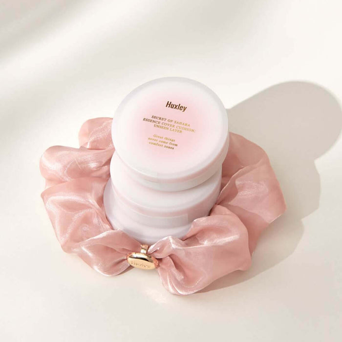HUXLEY Essence Cover Cushion Unseen Layer displayed with elegant pink silk fabric backdrop.