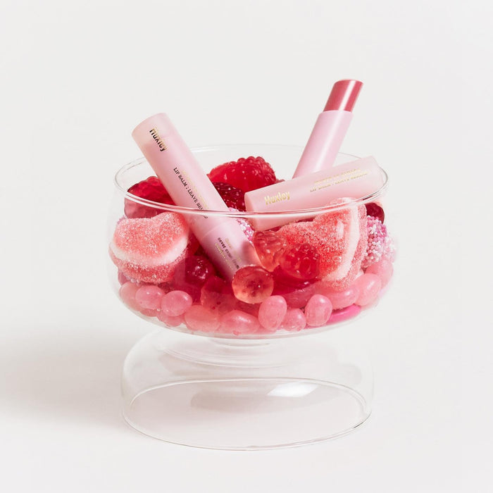 HUXLEY Lip Balm Leave Behide in glass bowl with pink decorative candies