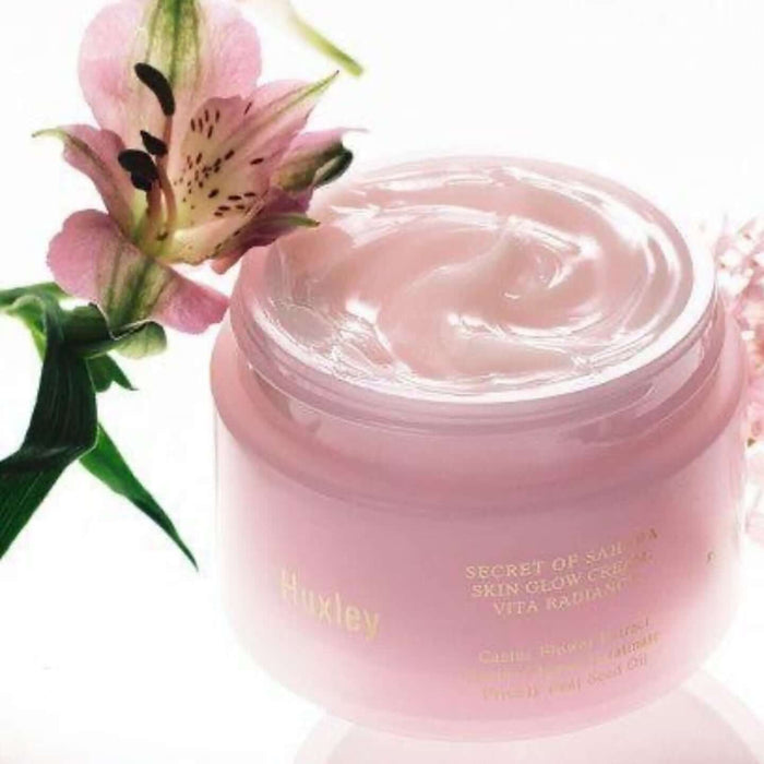 Open jar of HUXLEY Skin Glow Cream Vita Radiance with floral design, showcasing smooth texture for revitalized skin care