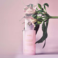 HUXLEY Skin Glow Essence Vita Radiance with floral background, glowing serum bottle promoting radiant skin.
