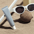 HUXLEY Sun Cream Stay Sun Safe SPF50+ PA++++ 30ml on sandy beach with sunglasses
