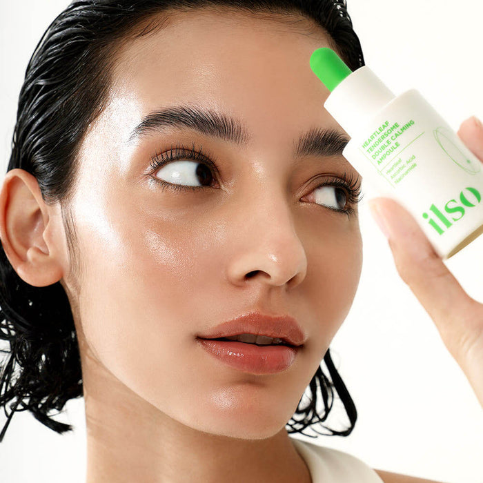Woman using ILSO Eoseongcho Tenderjom Double Calming Ampoule 30ml for skincare routine, close-up.