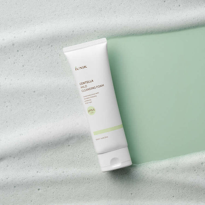 iUNIK Centella Mild Cleansing Foam 120ml tube on a foamy green background, showcasing skincare product packaging.