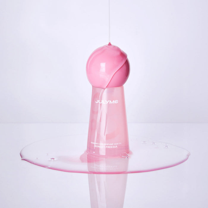 JULYME Damage Care Perfume Hair Oil 30ml (Sunset Freesia) pink bottle with spilled oil effect on white background