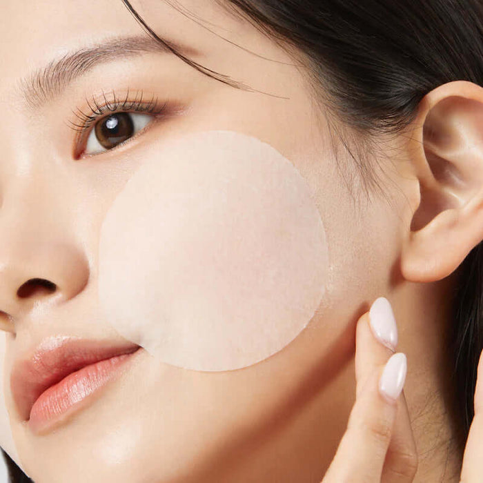 Woman using JUMISO Antioxidant Glow Toning Pads 70 Sheets on cheek for skincare routine