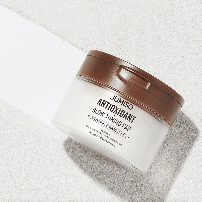 JUMISO Antioxidant Glow Toning Pads 70 Sheets in a white container with brown lid on a light background