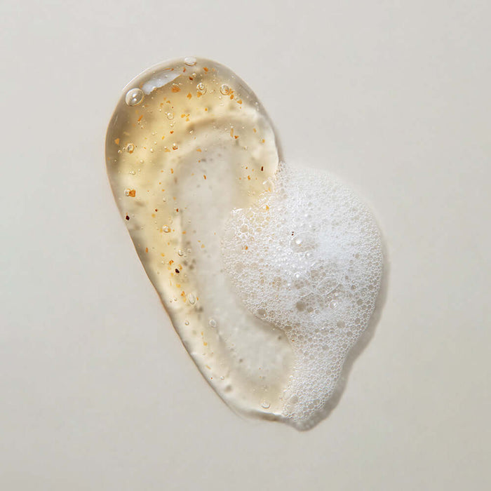 Texture of KAINE Kombu Hydrating Daily Cleanser 155g with foam and exfoliating particles on a light background.