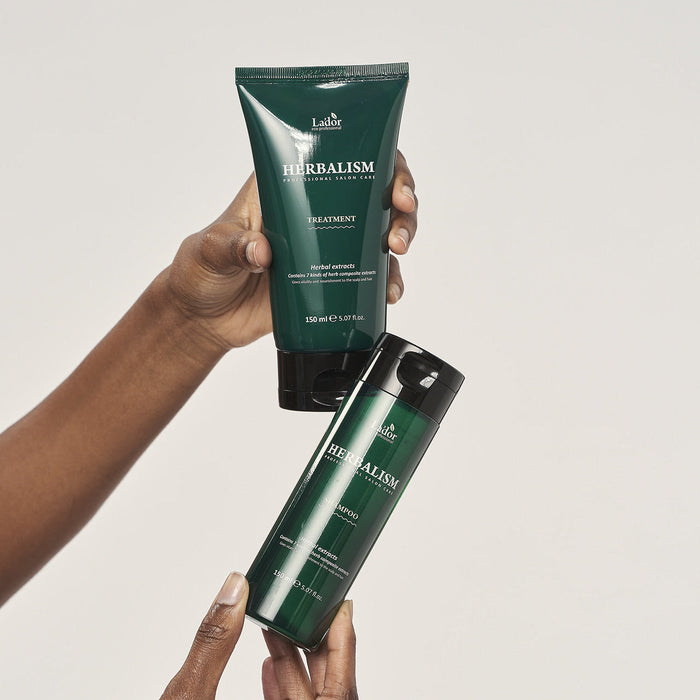 Two bottles of LADOR Herbalism Treatment 150ml being held.