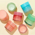 Assorted LANEIGE Lip Sleeping Mask EX jars on display in different colors and flavors, including berry, grapefruit, and mint choco.