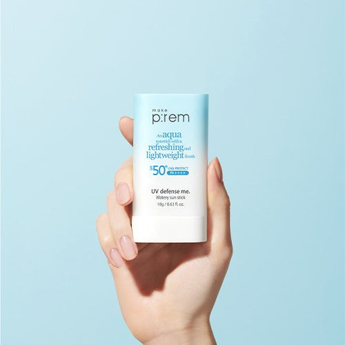 Hand holding MAKE P:REM UV Defense Me Watery Sun Stick 18g SPF50+ PA++++ against blue background.