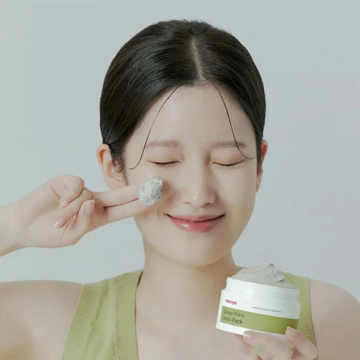 Smiling woman applying MANYO Deep Pore Soda Pack 110ml to her face, showcasing skincare benefits.