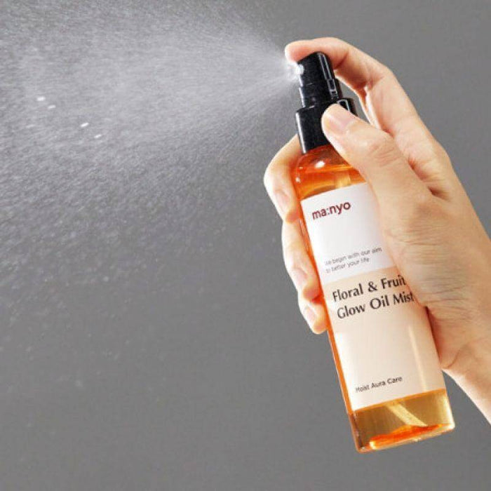 MANYO Floral & Fruit Glow Oil Mist 150ml being sprayed from a bottle, highlighting the product's hydrating qualities.