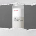 MA:NYO Galactomy Clearskin Toner 210ml bottle on torn paper background.