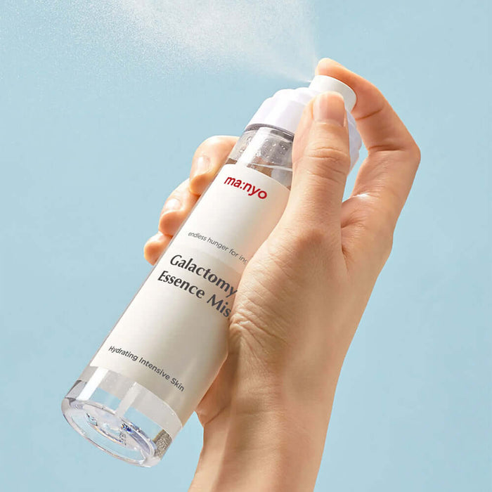 MANYO Galactomy Essence Mist 120ml being sprayed, showcasing hydrating benefits for intensive skin care on a light blue background.