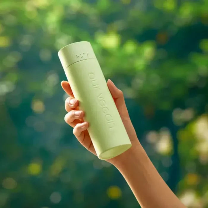 Person holding MANYO Our Vegan Heartleaf Moisture Soothing Toner 315ml against a green background