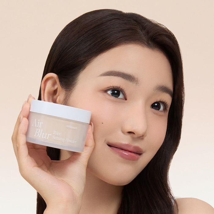 Woman holding MILK TOUCH Air Blur Rice Setting Powder with a smile