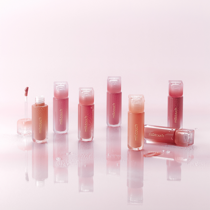 MILK TOUCH Dew Stain Sheer Lip Gloss collection in various shades on a glossy surface.