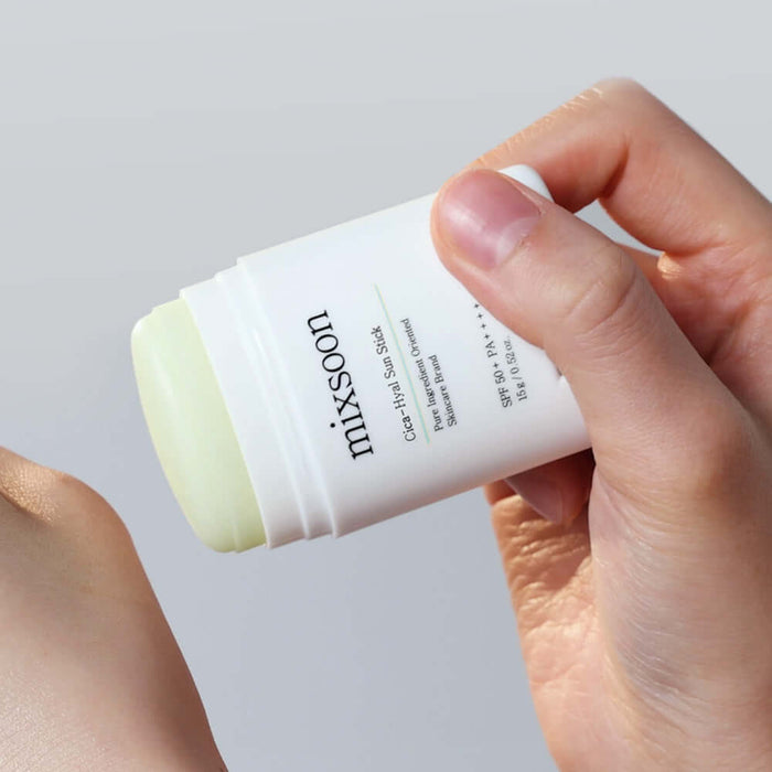Hands holding MIXSOON Cica Hyal Sun Stick for skincare and sun protection