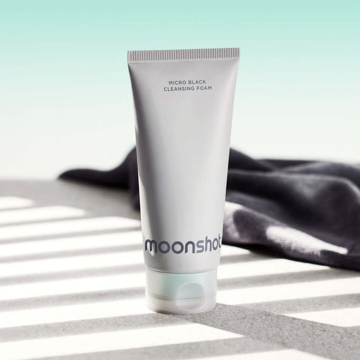 MOONSHOT Micro Black Cleansing Foam tube on a sunny surface with shadows.