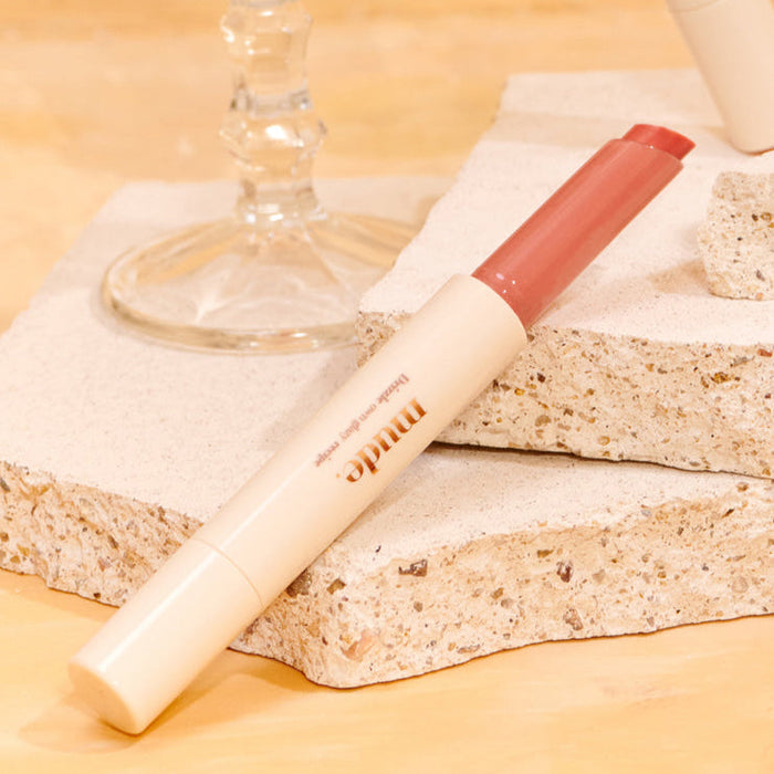 MUDE Drizzle Night lip product on stone surface