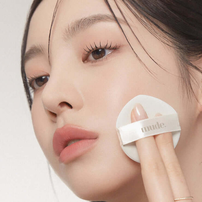 Woman applying MUDE Soft Silky Fit Cushion to her face for a flawless finish.