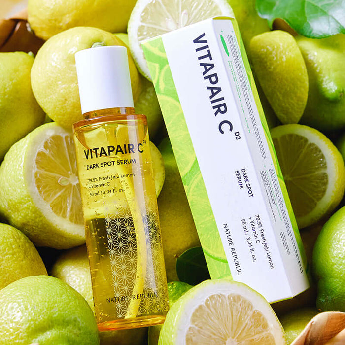 NATURE REPUBLIC Vitapair C Spot Serum 90ml Large Capacity 90ml bottle and box surrounded by fresh lemons.