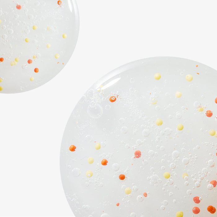 Close-up of NEOGEN Dounble Viita Capsual Cleansing Foam 150ml texture with vibrant orange and yellow capsules on a white background.