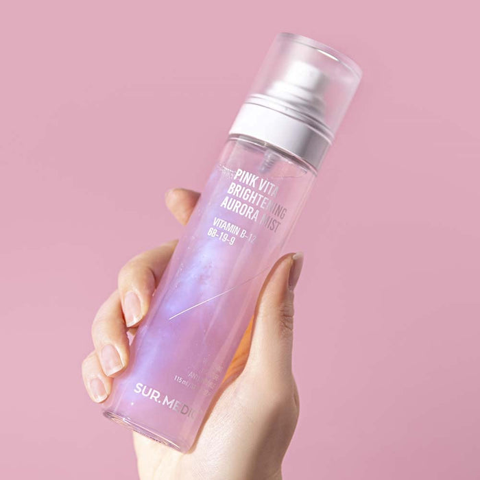 Hand holding NEOGEN Pink Vita Aurora Mist 115ml against a pink background