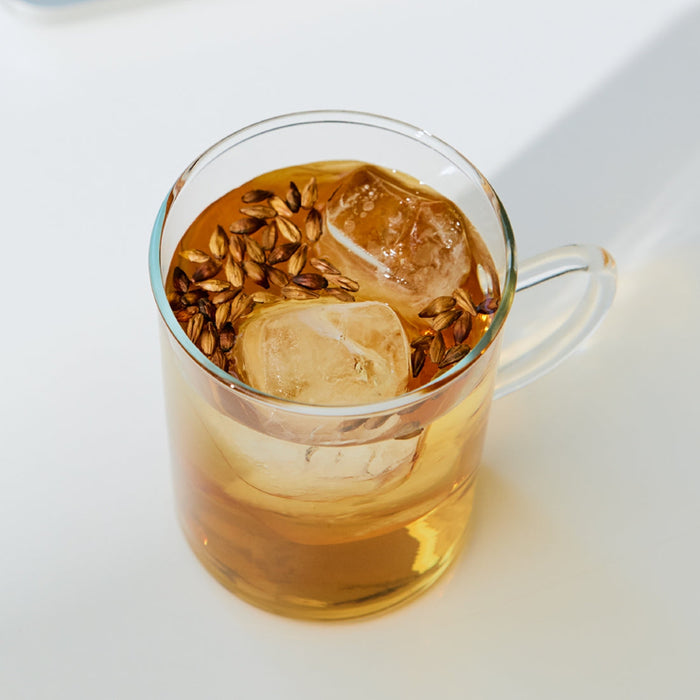 Glass cup of iced herbal tea with floating seeds on a white surface